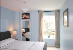 1 dormitorio con paredes azules, 1 cama y ventana en LuxApartment - Port Of Leith - Free Parking, en Edimburgo
