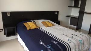 1 dormitorio con 1 cama grande con almohadas amarillas en Punta 28 en Las Gaviotas