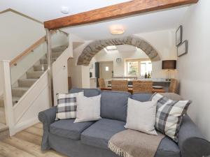 ein Wohnzimmer mit einem blauen Sofa und einer Treppe in der Unterkunft 1 Grosvenor Farm Cottages in Skipton