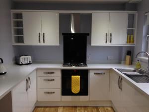 a kitchen with white cabinets and a yellow oven at Flat Three, 212 Eaglesham Road, East Kilbride, Glasgow in East Kilbride