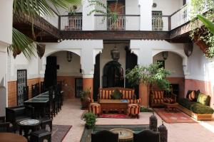 a courtyard of a building with chairs and tables at Riad Jnan El Cadi in Marrakech