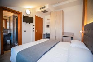 a bedroom with a white bed and a clock on the wall at Hotel Gabbiano in Rimini