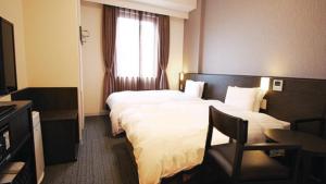 a hotel room with two beds and a window at Dormy Inn Higashi Muroran in Muroran