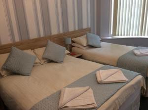 two beds in a hotel room with towels on them at Beaucliffe continental in Blackpool