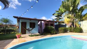 a villa with a swimming pool in front of a house at Pousada Caravelas in São Miguel do Gostoso