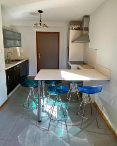 a kitchen with a white table and four blue stools at Le Nid in Vaujany