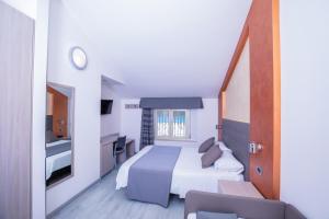 a hotel room with a bed and a desk and a window at Hotel Gabbiano in Rimini