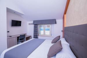 a bedroom with a bed and a desk and a window at Hotel Gabbiano in Rimini