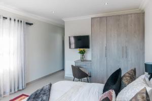 a bedroom with a bed and a cabinet with a television at Elizabeth House in Hermanus