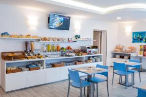 a restaurant with blue chairs and a counter with food at Hotel Gabbiano in Rimini
