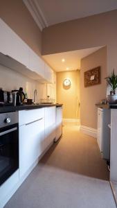 una cocina con armarios blancos y un reloj en la pared en Great 1 Bed Walking Distance To Whiteladies Road en Bristol