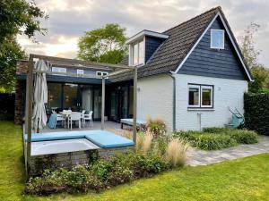 a house with a patio with a table and an umbrella at Heerlijk vrijstaand huis aan de duinen in Burgh Haamstede