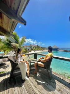 duas pessoas sentadas numa mesa num deque com vista para o oceano em Curacao Avila Beach Hotel em Willemstad