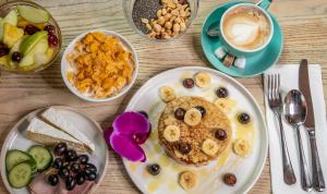 a table with plates of food and a cup of coffee at The Corner London City in London