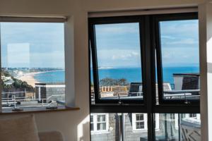 two windows in a room with a view of the ocean at Westcliff Penthouse in Bournemouth