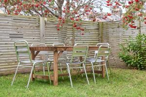 a wooden table with four chairs and a fence at Host & Stay - The Old Workhouse in Alnwick