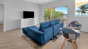 a living room with a blue couch and a tv at 3-Bedroom, 2-Bath Beachfront Condo with Pool in Playa Flamingo