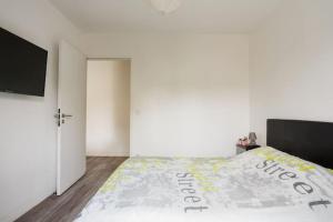 Un dormitorio blanco con una cama con un cartel. en L'escapade parisienne, en Aulnay-sous-Bois