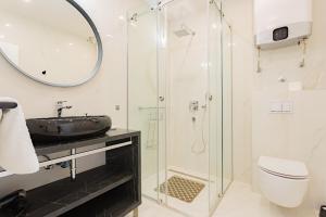 uma casa de banho com uma cabina de duche em vidro e um lavatório. em Apartmani Benzon em Baska Voda