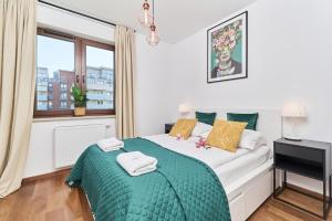 ein Schlafzimmer mit einem Bett mit einer grünen Decke und einem Fenster in der Unterkunft Nowa Tęczowa Apartments Promenada Staromiejska by Renters in Breslau