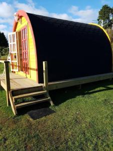 a small shed with a door and a bench in the grass at Lovely Glamping Dream Pod in St Austell Cornwall in St Austell