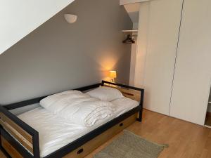 um pequeno quarto com uma cama com lençóis brancos em Maison de village avec jardin 15mn des plages, wifi, 2 chambres, jardin em Hesdin-lʼAbbé