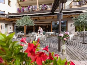 a woman sitting at a table on a patio with flowers at Hotel Zentral ****superior in Kirchberg in Tirol