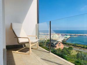 une chaise blanche assise sur un balcon donnant sur l'océan dans l'établissement Apartamentos la Marosa Delux, à Burela