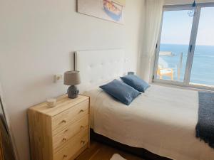 a bedroom with a bed and a window with the ocean at Apartamentos la Marosa Delux in Burela de Cabo