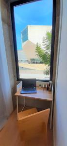 Una computadora portátil sobre un escritorio frente a una ventana. en Boavista Class Inn, en Oporto