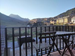 un balcone con tavolo, 2 sedie e griglia di Apartamentos Pirineos Rent a Candanchú