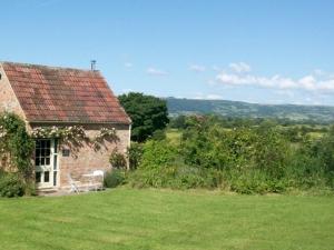 a small stone house with a chair in a field at Pass The Keys Ian's Cottage, Wedmore - country cottage for two in Wedmore