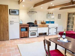 a large kitchen with a table and a refrigerator at Pass The Keys Goose Feather Barn, Wedmore luxury cottage for two in Wedmore