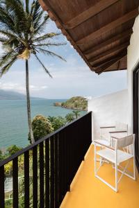 einen Balkon mit 2 Stühlen und einer Palme in der Unterkunft Miradouro de São Sebastião in São Sebastião