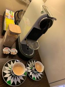 a coffee machine with two cups of coffee on plates at Budapest Downtown in Style - Luxury Apartment in Budapest