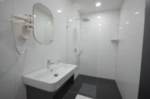 La salle de bains blanche est pourvue d'un lavabo et d'un miroir. dans l'établissement N9 Hotels, à Nuremberg