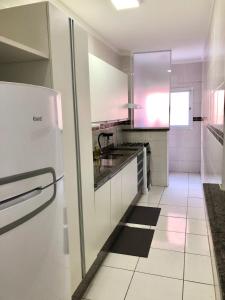 uma cozinha branca com um frigorífico e piso em azulejo em Vip Residencial - Praia Grande na Praia Grande
