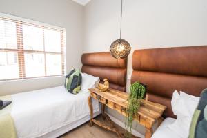 a room with a bed and a table with a bench at Plettenberg Bay Unit 10 Whale Rock Gardens Apartment in Plettenberg Bay +30 photos