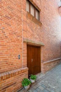 a brick building with a door and two potted plants at Apartamenty przy Ścieżce Kościelnej in Elblag +2 photos