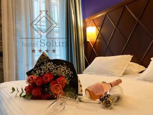 a hotel room with a bottle of wine and flowers on a bed at Hotel Solun in Trieste