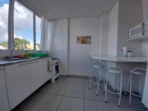 a kitchen with white cabinets and a sink and stools at Villa Tata Suítes Ltda in Curitiba