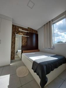 庫里奇巴的住宿－Villa Tata Suítes Ltda，一间卧室设有一张大床和一个窗户。