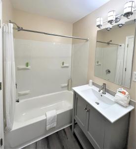 a bathroom with a tub, sink, and shower stall at Coastal Inn and Suites in Long Beach