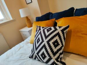 a bed with orange and blue pillows and a window at Newhall Street Apartment in Birmingham