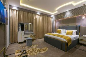 Schlafzimmer mit einem Kingsize-Bett und einem TV in der Unterkunft Lambert ApartHotel in Dschidda