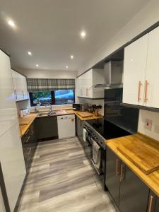 uma cozinha com armários brancos e electrodomésticos pretos em Amazing Alps and Loch views - HOT TUB and pet friendly em Arrochar