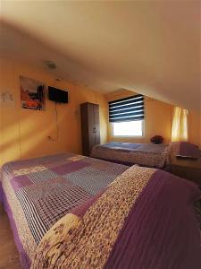 a bedroom with two beds and a tv on the wall at Hostal Del Tuto in Punta Arenas