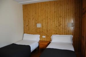 a room with two beds and a wooden wall at Pension Casa Vicenta in Vielha