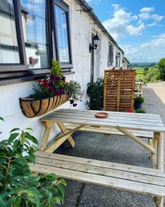 - une table de pique-nique en bois à côté d'un bâtiment fleuri dans l'établissement Little Park Holiday Homes Self Catering Cottages 1 & 2 bedrooms available close to Tutbury Castle, à Tutbury
