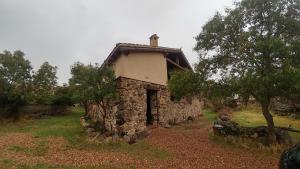 an old stone house sitting in a field at Casa Rural el Pajar de Tenzuela in Pelayos del Arroyo